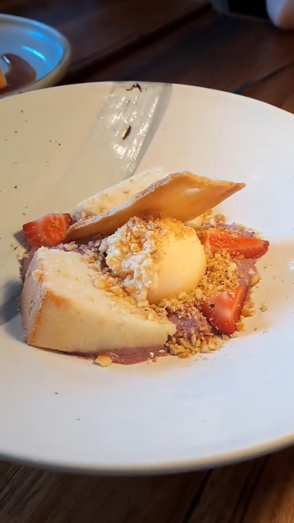 A dessert with ice cream, crumble and strawberries