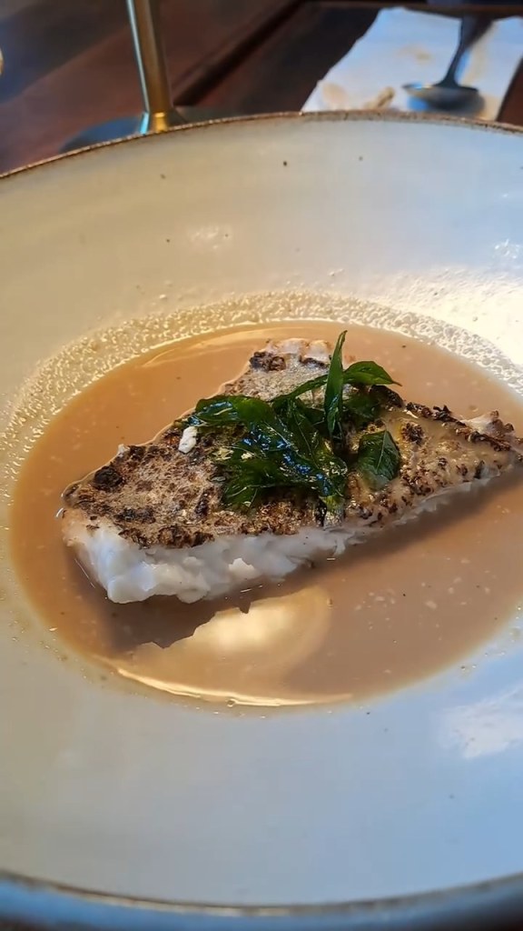 Fish fillet in a creamy broth topped with herbs