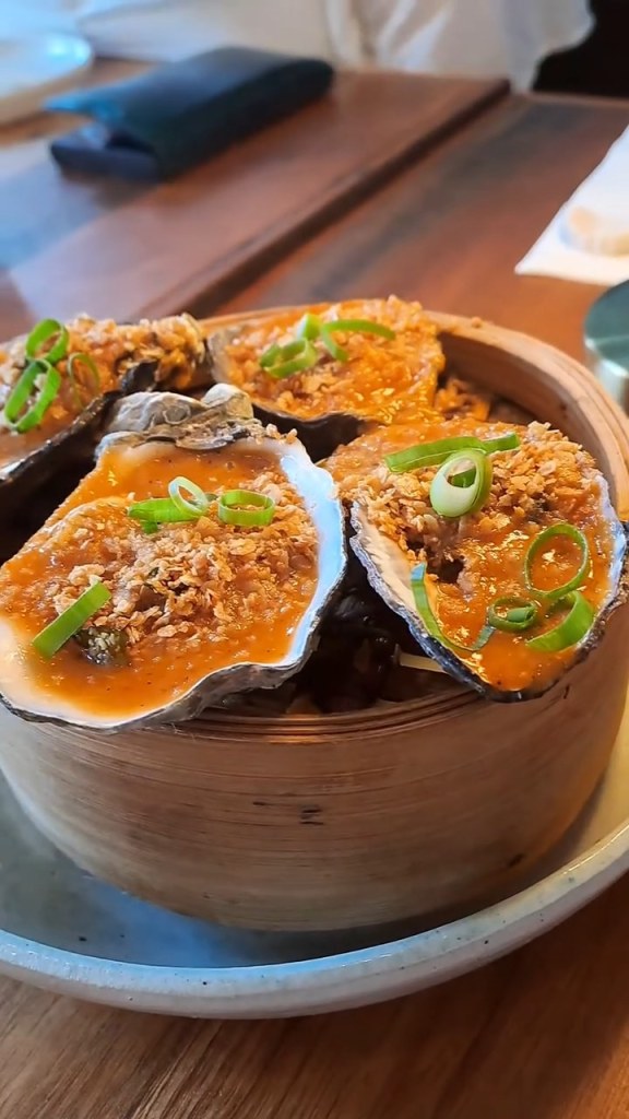 Oysters topped with crispy garlic and spring onion in a steamer basket