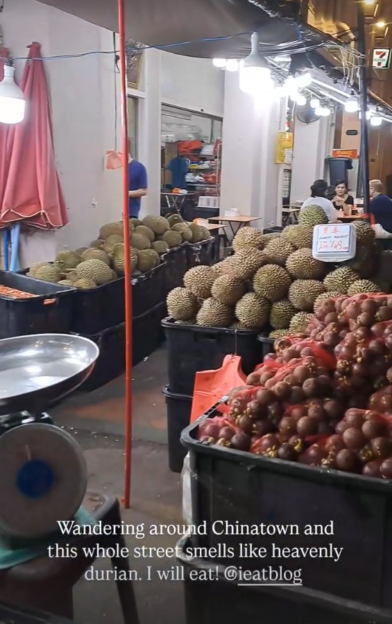 Durian and mangosteen piled high at a Chinatown fruit stall at night