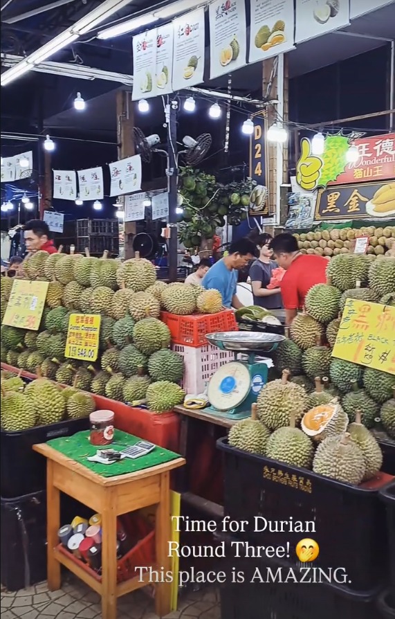 A durian stall with piles of durian under bright lights
