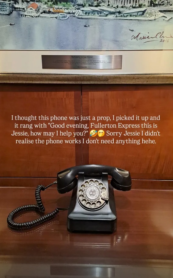 A black rotary phone on a timber desk in the hotel