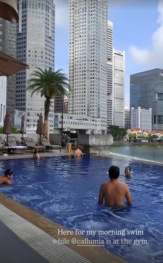 Swimmers in the pool with city towers behind