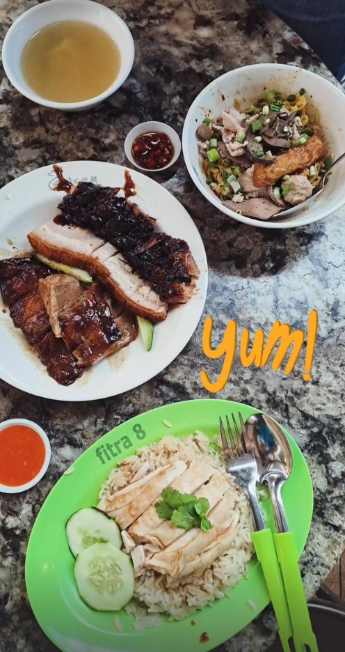 Roast meats, chicken rice and a bowl of noodles on a marble table