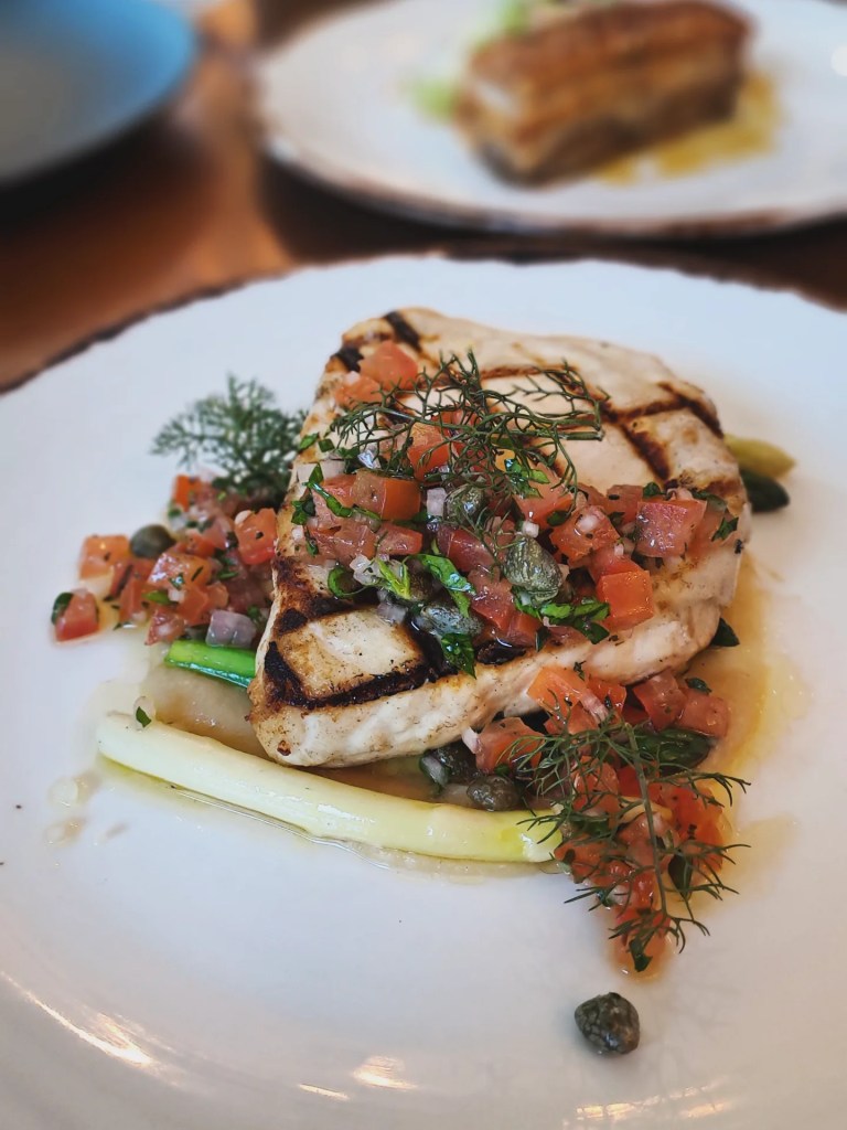 Grilled fish topped with tomato salsa and dill