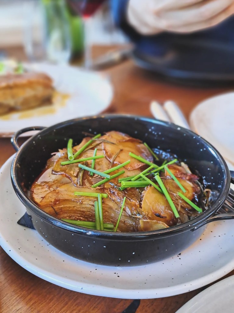 A skillet of layered potatoes topped with chives