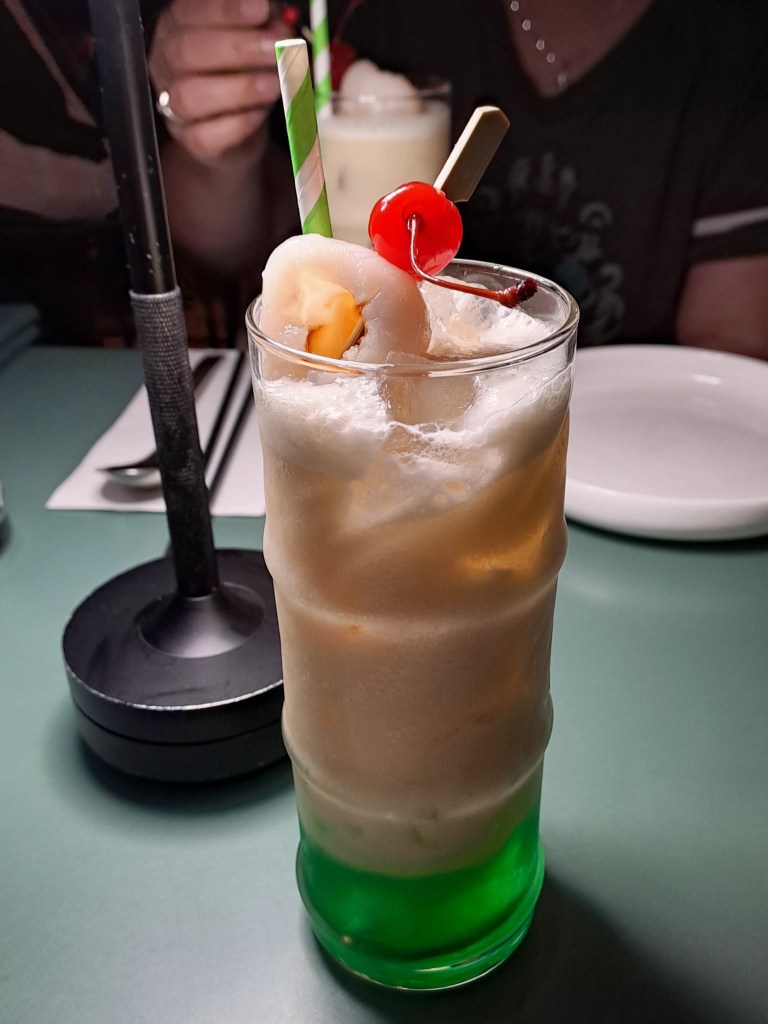 A creamy green layered drink topped with a cherry